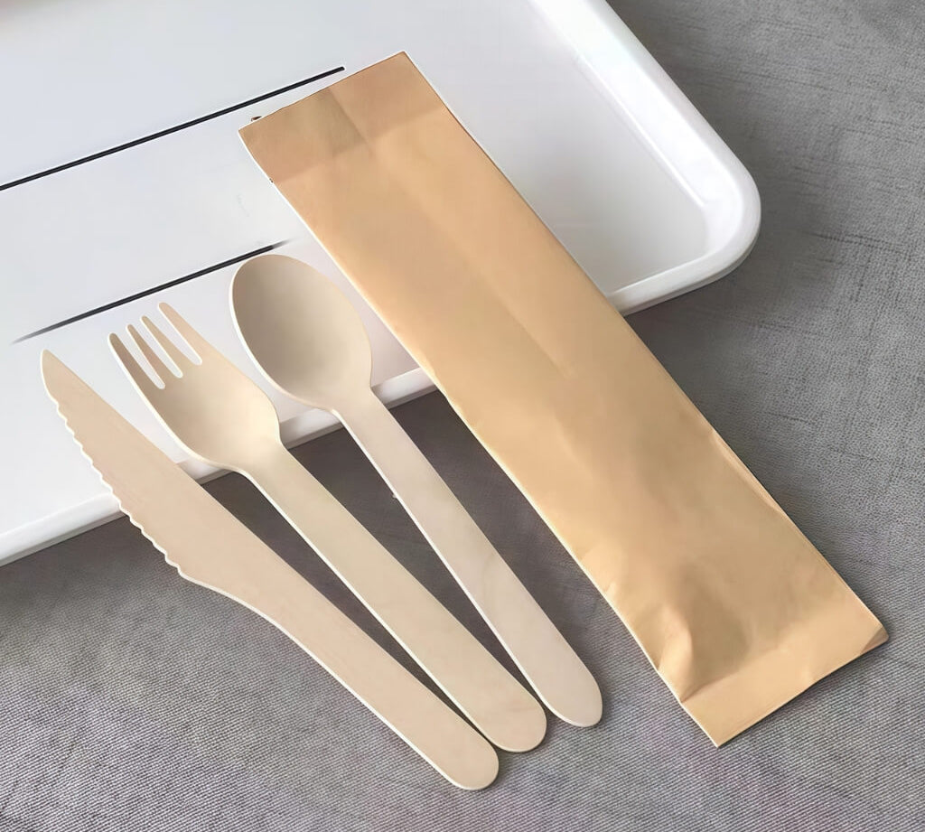 Disposable wooden cutlery set with knife, fork and spoon in kraft paper sleeve, for kids party table settings.