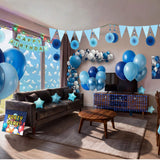 Living room fully decorated for a kids birthday party with blue balloon garland, paper fans, happy birthday bunting, star balloons, backdrop and table cover from a OneStopBox party decorations kit.