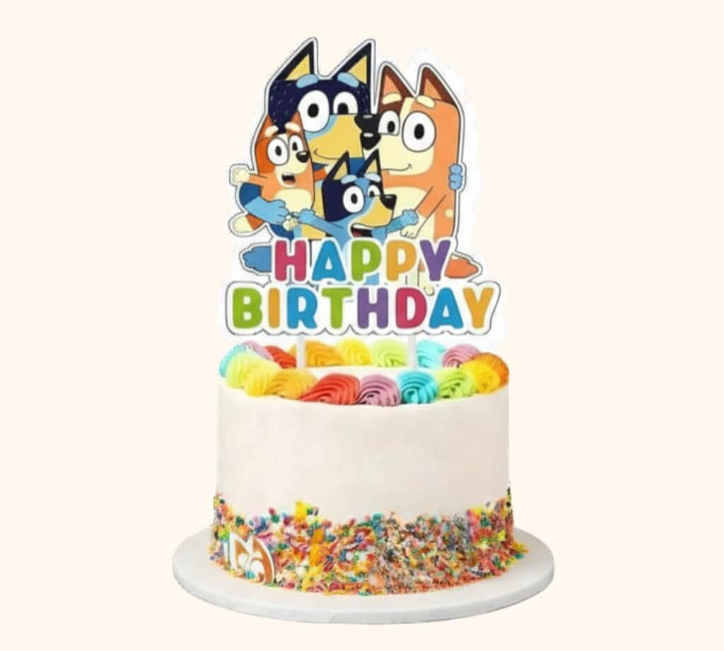 Bluey happy birthday cake topper on a white celebration cake with rainbow rosettes and rainbow sprinkles, for kids party decorations.