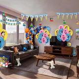 Complete Bluey themed kids birthday party decorations filling a living room, including character printed balloons, balloon garland, triangle bunting, honeycomb hangings, happy birthday banner, backdrop, table cover and plush toys from a OneStopBox all-in-one party kit.