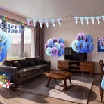 Living room decorated for a Frozen themed girls birthday party with character printed balloons in blue and purple, triangle bunting, happy birthday banner, backdrop and snowflake table cover from a OneStopBox party decorations kit.