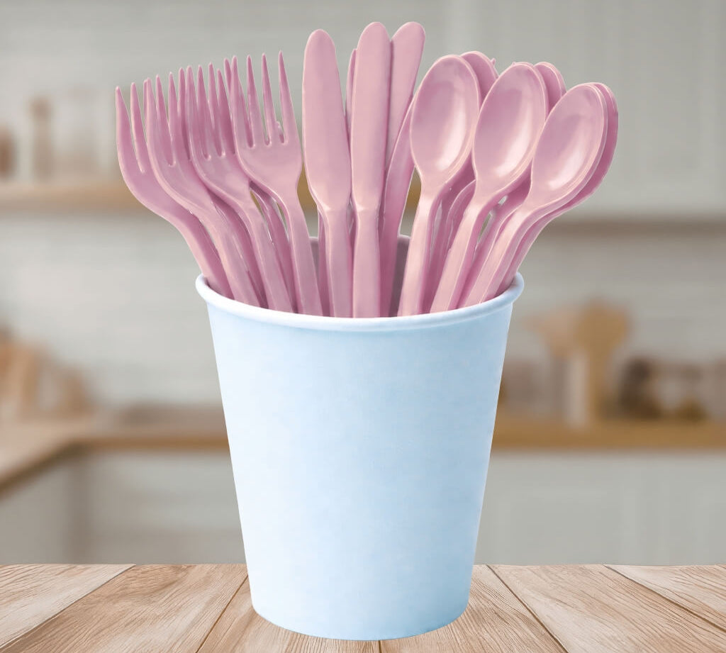 Light Pink reusable plastic cutlery set in a light blue cup on a wooden table.