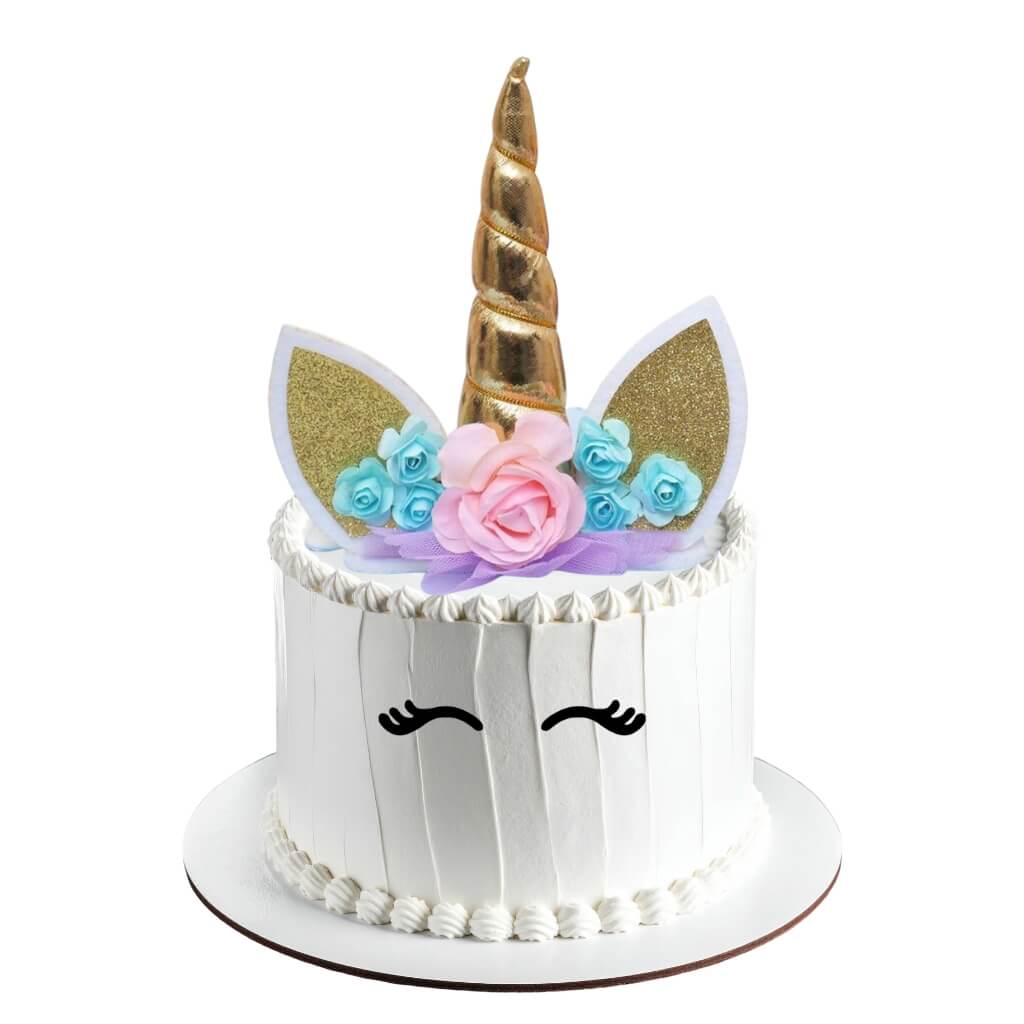 Unicorn-themed cake topper with gold horn, floral decorations, and white face with black eyes on a white background