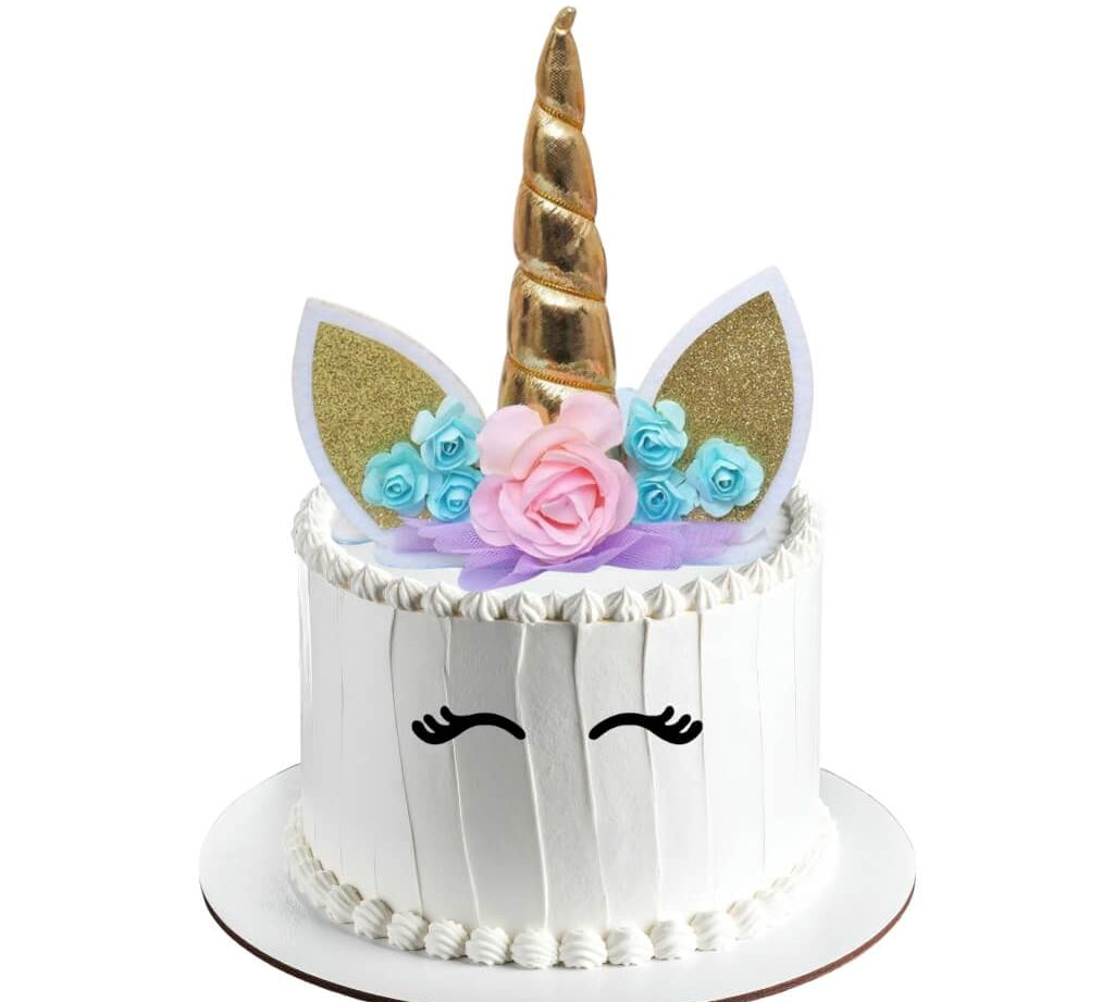 Unicorn-themed cake topper with gold horn, floral decorations, and white face with black eyes on a white background
