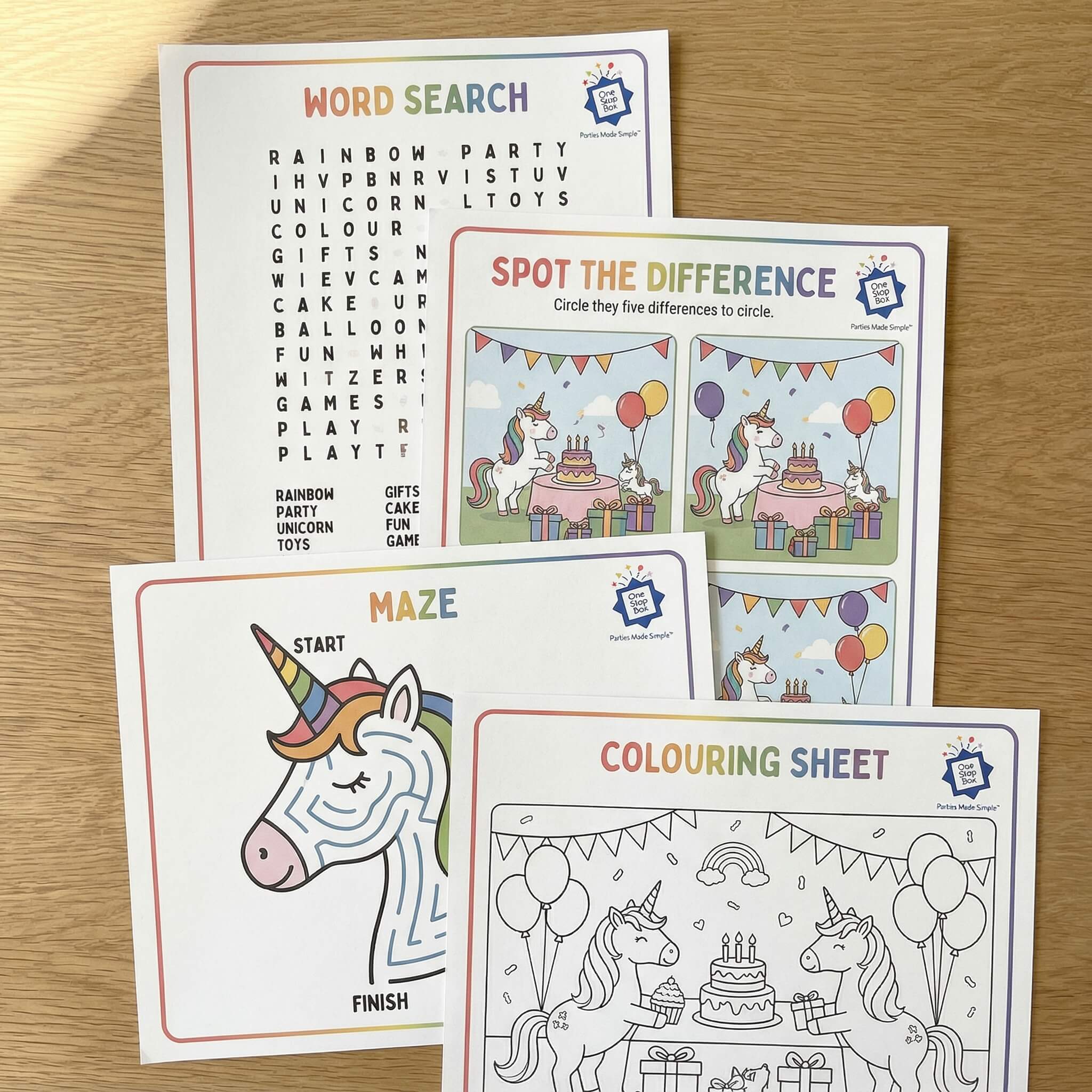 Educational activity sheets with unicorn theme on a wooden surface including word search, colouring and spot the difference