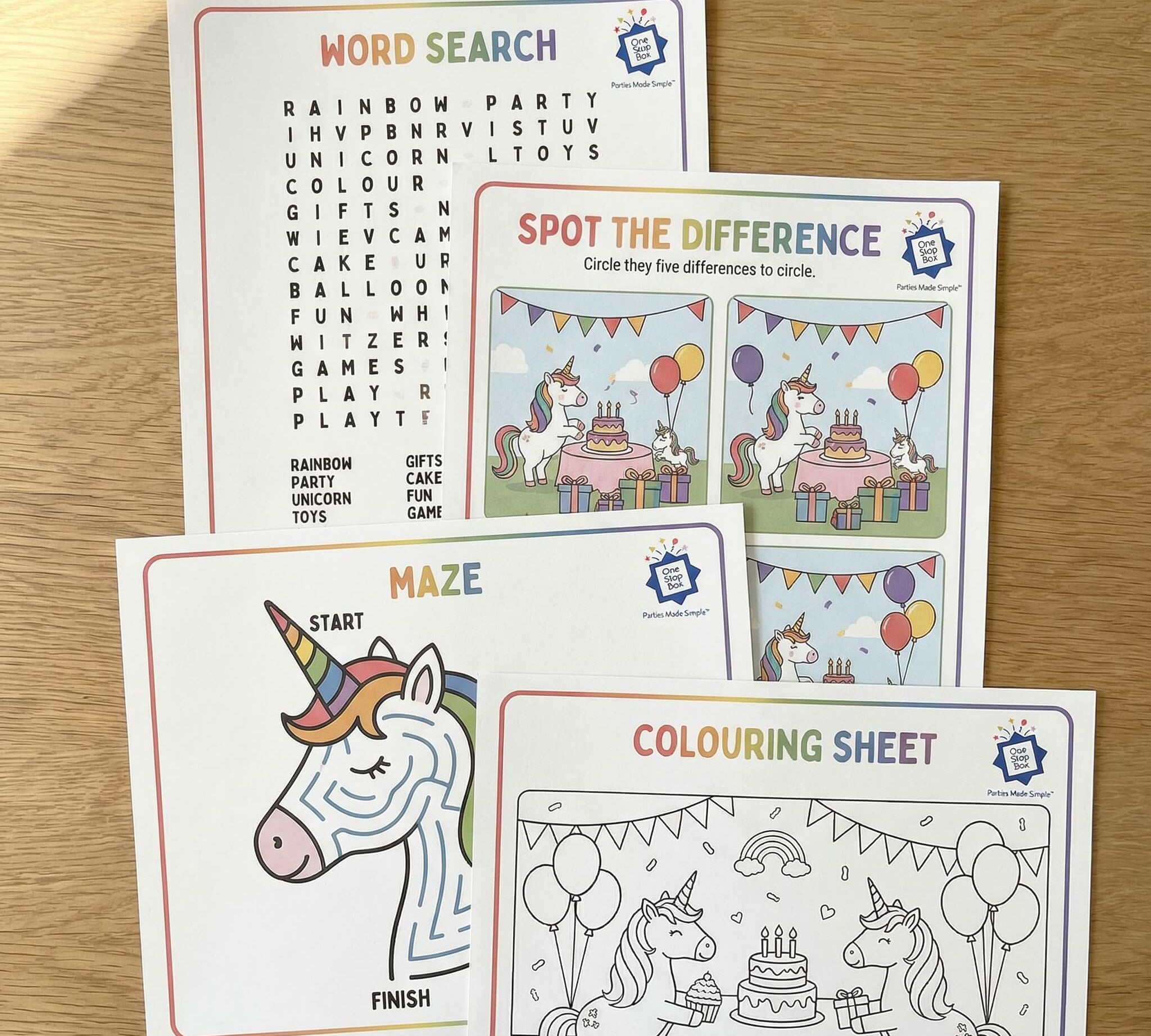 Unicorn rainbow themed activity sheets on a wooden surface including word search, colouring and spot the difference